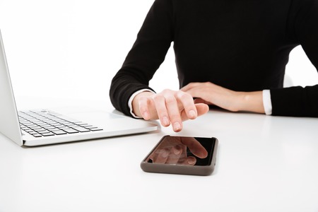 Cropped image of young business lady sitting at the table isolated over white background using...