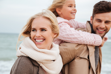 Portrait of a joyful family with a little daughter having fun at the beach togetherの写真素材