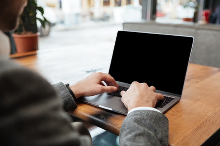 Cropped image of business man sitting by the table in cafe and typing in laptop computerの写真素材