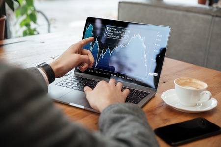 Cropped image of business man sitting by the table in cafe and analyzing indicators on laptop computerの写真素材