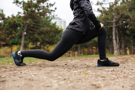 Cropped image of a fitness girl stretching legs outdoorsの写真素材