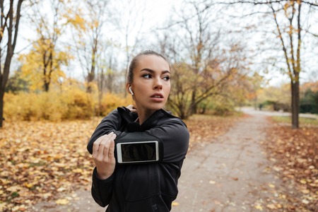 Portrait of a young fitness girl in earphones working out at the park