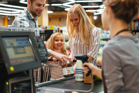 Happy family standing at the cash counter buying groceries at the supermarketの写真素材