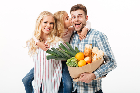 Portrait of a happy family holding paper shopping bag full of groceries isolated over white backgroundの写真素材