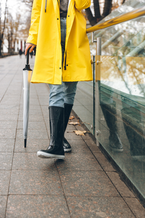 Cropped photo of young woman dressed in raincoat walking outdoors.の写真素材