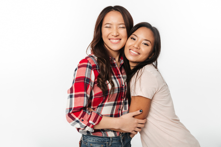 Image of two asian pretty cheerful ladies sisters hugging with each other. Looking camera.の写真素材