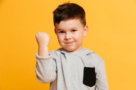 Photo of little boy child standing isolated over yellow background. Looking camera gesturing with...