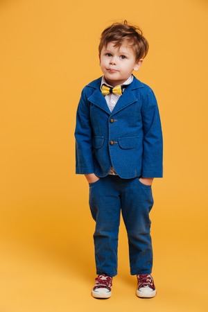 Image of little confused boy child standing isolated over yellow background. Looking camera.の写真素材