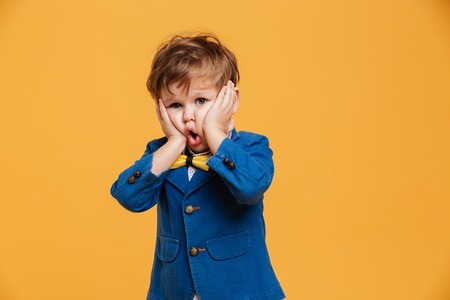 Image of shocked screaming boy child standing isolated over yellow background. Looking camera.の写真素材