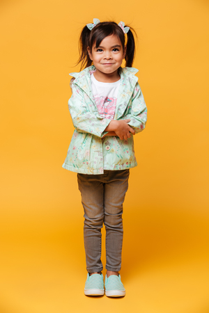 Photo of smiling little girl child standing isolated over yellow background.の写真素材