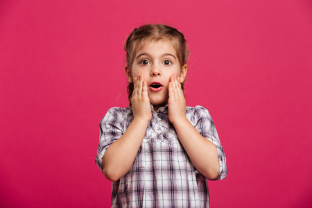 Photo of shocked cute little girl child standing isolated over pink background.の写真素材