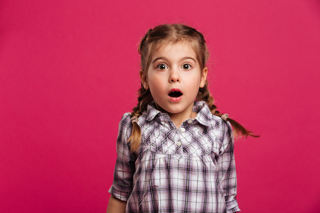 Picture of shocked little girl child standing isolated over pink background.の写真素材