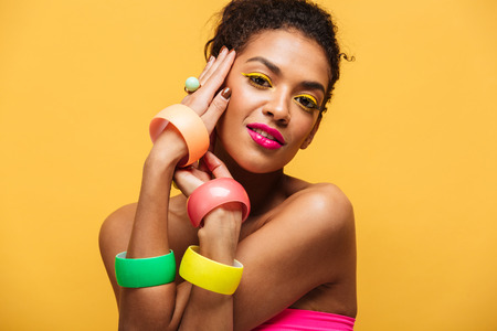 Fashion portrait of beautiful african american woman with bright makeup demonstrating multicolour...