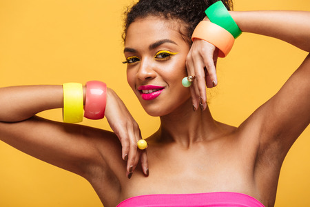 Fashion portrait of attractive african american woman with bright makeup showing jewelry on her...