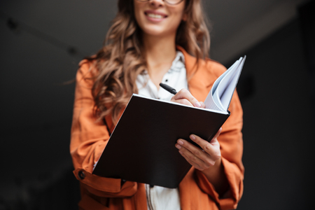 Close up portrait of a smiling woman making notes in a notepad outdoorsの写真素材