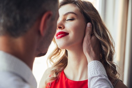 Back view of man hug and touch his woman while standing near windowの写真素材