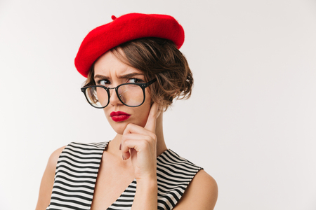 Portrait of a disappointed woman wearing red beret and eyeglasses looking at camera isolated over white backgroundの写真素材