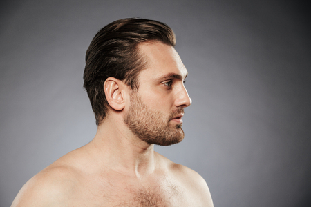 Side view portrait of a sexy shirtless man looking away isolated over gray backgroundの写真素材
