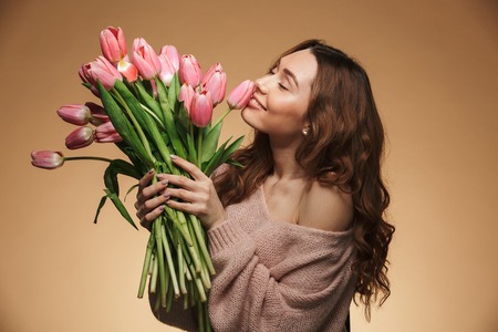 Image of pretty young woman standing isolated holding tulips flowers. Looking camera.の写真素材