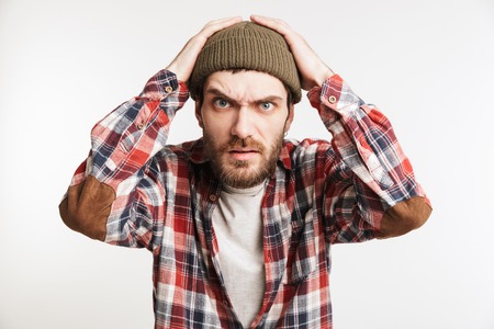 Portrait of a frustrated bearded man in plaid shirt looking at camera isolated over white backgroundの写真素材