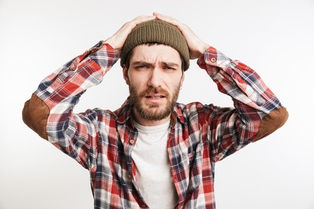 Portrait of a confused bearded man in plaid shirt looking at camera isolated over white backgroundの写真素材