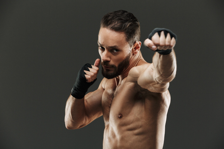 Portrait of a focused muscular sportsman boxing over gray backgroundの写真素材