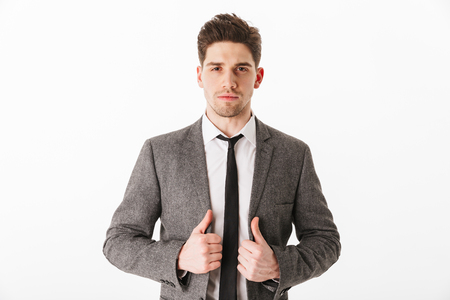 Cool serious business man holding jacket and looking at the camera over white backgroundの写真素材