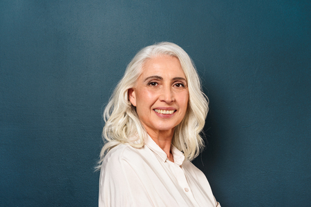 Photo of gorgeous mature old woman standing isolated over dark blue background wall looking camera.の写真素材
