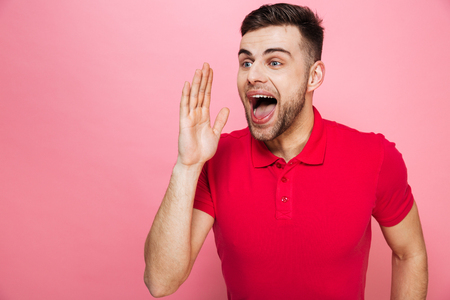 Portrait of a happy young man screaming isolated over pink backgroundの写真素材