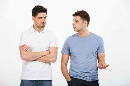 Portrait of two upset young men arguing isolated over white backgroundの写真素材