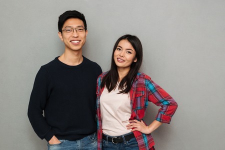 Image of happy young asian loving couple standing isolated over grey wall background looking camera.の写真素材