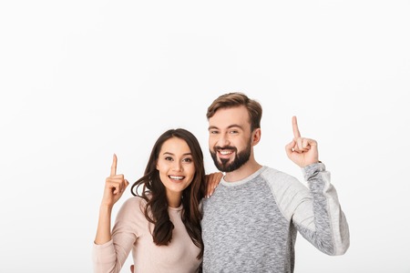 Image of cheerful young loving couple isolated over white wall background. Looking camera pointing.