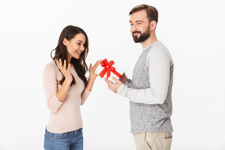 Image of happy young man standing with surprise box for his woman isolated over white background wall.の写真素材