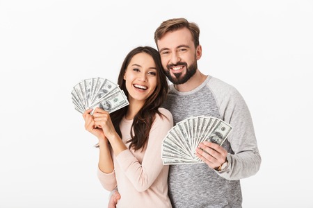 Photo of happy young loving couple standing isolated over white background holding money.の写真素材