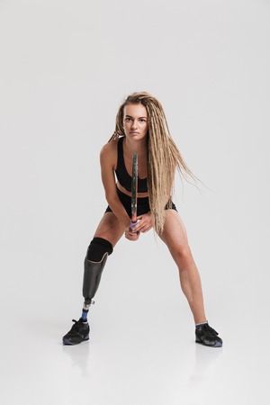 Image of a healthy young disabled sportswoman tennis player standing isolated over grey background play tennis.の写真素材