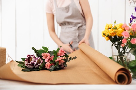 Cropped photo of florist woman standing near table working with flowers in workshop.の写真素材