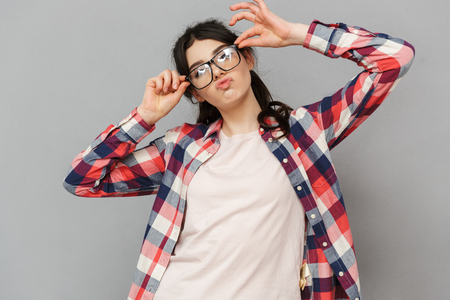 Image of funny cute young lady in glasses standing isolated over grey background wall.の写真素材