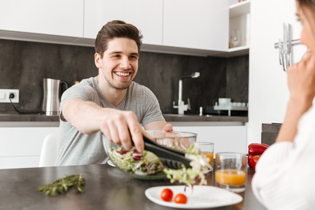 Portrait of a happy young man having healthy breakfast with a her girlfriend at kitchenの写真素材