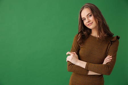 Image of happy young woman standing isolated over green background looking camera.