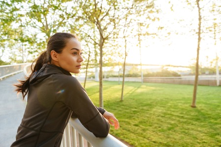 Picture of gorgeous beautiful young asian sports woman looking aside outdoors.