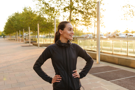 Picture of cheerful beautiful young asian sports woman looking aside outdoors.の写真素材