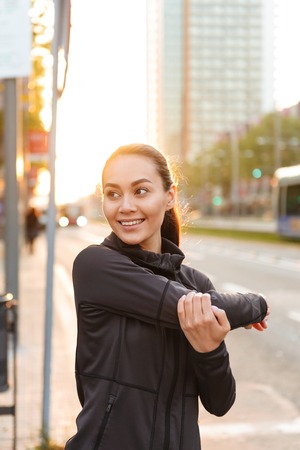 Image of cheerful young asian sports woman make stretching exercises outdoors.