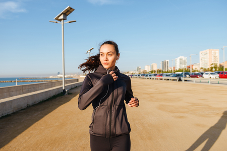 Photo of amazing beautiful young asian sports woman running outdoors listening music.の写真素材