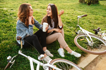 Photo of two young happy women friends outdoors with bicycles in park.の写真素材