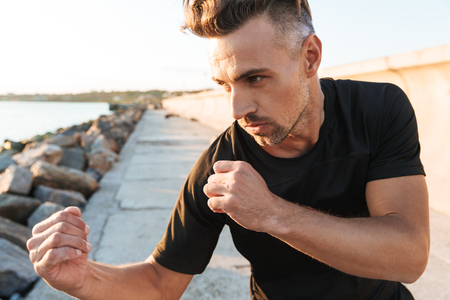Image of strong sportsman boxer make sport boxing exercises outdoors at the beach early morning.の写真素材