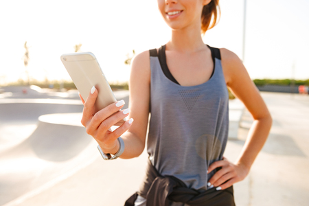 Cropped image of happy sports lady outdoors using mobile phone.の写真素材