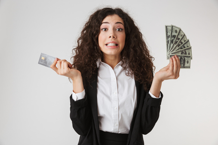 Photo of emotional young business woman with credit card and money isolated over white wall backgound.の写真素材