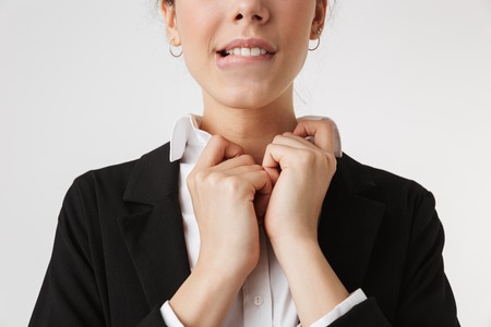 Cropped image of young business woman button his shirt isolated over white wall backgound.の写真素材