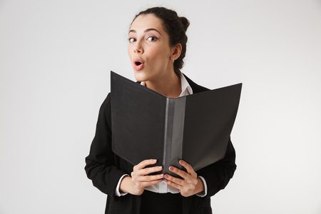 Photo of excited young business woman holding folder isolated over white wall backgound.の写真素材