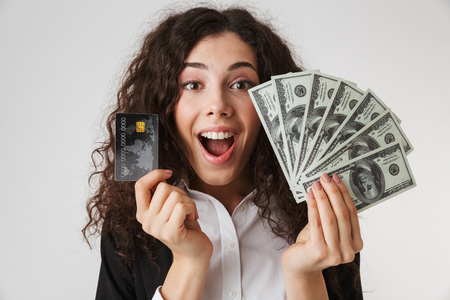 Photo of excited happy young business woman with credit card and money isolated over white wall backgound.の写真素材
